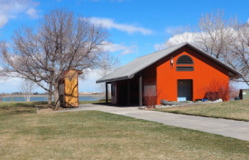 red pole barn by a lake and grass area